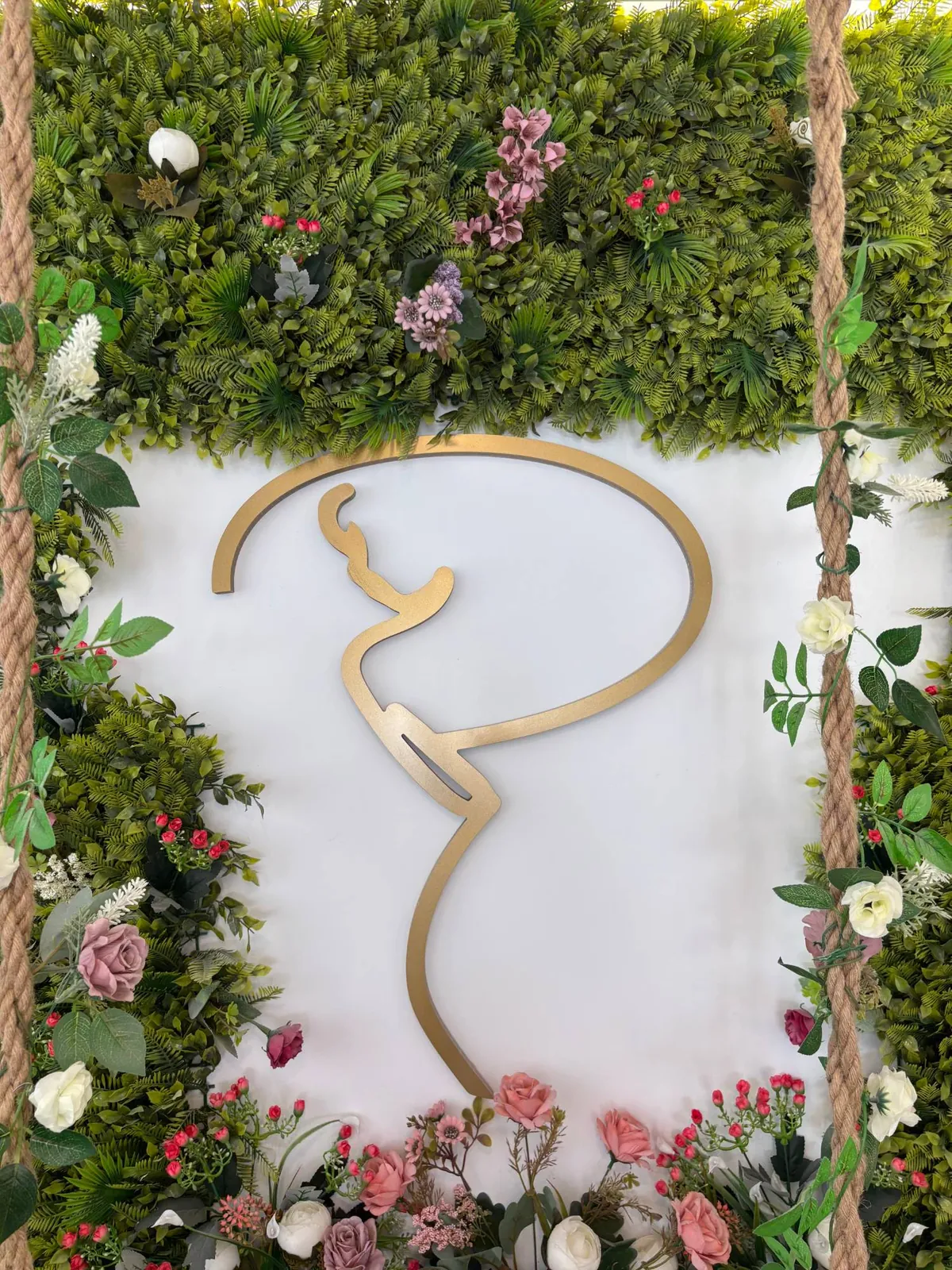 Logotipo dorado de Privilegios sobre el muro de flores